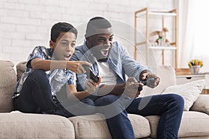 Cheerful Black Father And Son Competing In Video Games At Home