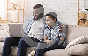 Cheerful Black Father And Son Watching Comedy Movie On Laptop Together