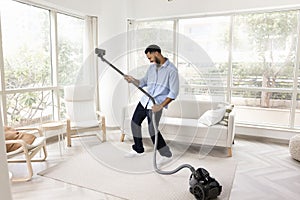 Cheerful Black homeowner guy having fun while tidying up