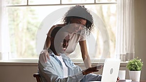 Cheerful black husband showing smiling wife funny video on laptop