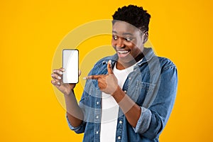 Cheerful Black Lady Showing Smartphone Screen Recommending Application, Yellow Background
