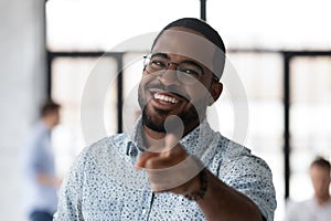 Cheerful black male hr looking at camera pointing to spectator