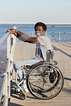 Cheerful Black man in wheelchair spending time at seafront photo