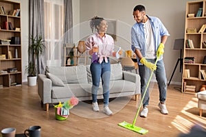 Cheerful Black Spouses Cleaning Living Room Doing Housework At Home