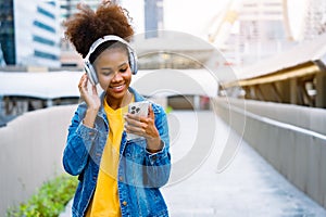 Cheerful black student girl wearing headset and using mobile smartphone