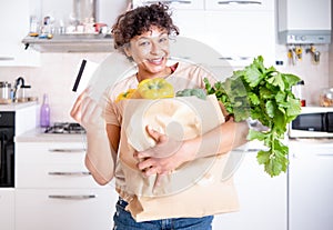 Cheerful black woman holding credit card and supermarket grocery paper bag