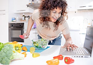 Cheerful black woman learning to cook at home watching online tutorial