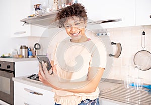 Cheerful black woman scrolling mobile phone in the morning at home