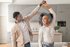 Cheerful black young couple dancing having fun at modern home