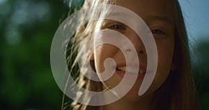 Cheerful blond girl posing in golden sunlight. Playful child looking in camera