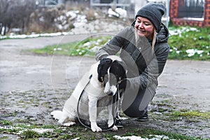 cheerful blond woman cuddling a lovely dog at the shelter, dog shelter and volunteer concept