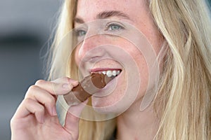 Cheerful blond woman eating chocolate