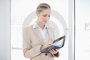 Cheerful blonde businesswoman writing on datebook