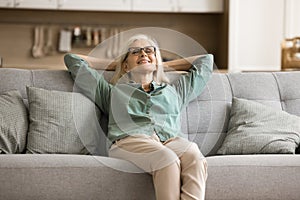 Cheerful blonde elderly woman in glasses enjoying comfort at home