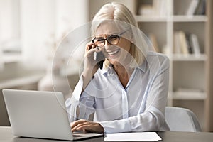 Cheerful blonde old business woman speaking on cellphone