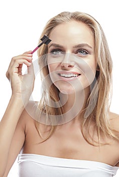 Cheerful blonde woman using eyebrows comb