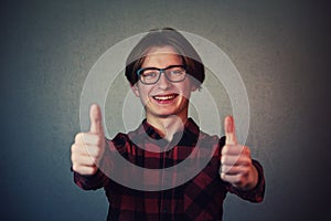 Cheerful boy adolescent showing double thumbs up, positive gesture, great feedback and approval, looking to camera with teeth