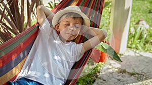 A cheerful boy, filled with smiles, swings and lounges in a garden hammock, radiating the aura of summertime, joyful