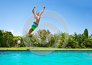 Cheerful boy jumping in outdoor swimming pool