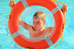 Cheerful boy looks through buoy from swimming-poo
