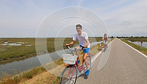 Cheerful boy pedaling bicycle on bicycle path with his mom