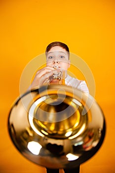 A cheerful boy plays the pipe blowing his cheeks. Humor playing a wind instrument