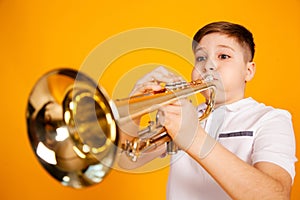 A cheerful boy plays the pipe blowing his cheeks. Humor playing a wind instrument