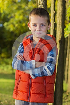 Cheerful boy in a red vest in the woods.