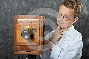 Cheerful boy retro photographer with vintage wooden camera