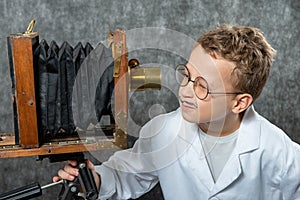 Cheerful boy retro photographer with vintage wooden camera