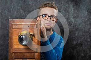 Cheerful boy retro photographer with vintage wooden camera