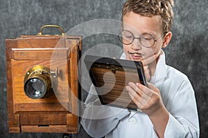 Cheerful boy retro photographer with vintage wooden camera