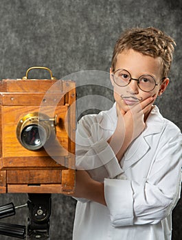 Cheerful boy retro photographer with vintage wooden camera