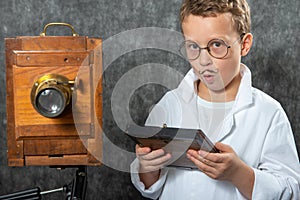 Cheerful boy retro photographer with vintage wooden camera