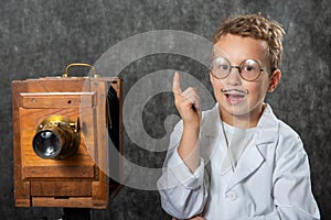 Cheerful boy retro photographer with vintage wooden camera