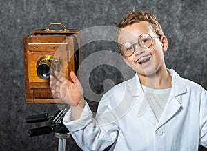 Cheerful boy retro photographer with vintage wooden camera