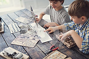 Cheerful boy smiling while his brother pointing to the instruction