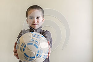 Cheerful boy with a soccer ball in his hand. Light background. European appearance. copy space