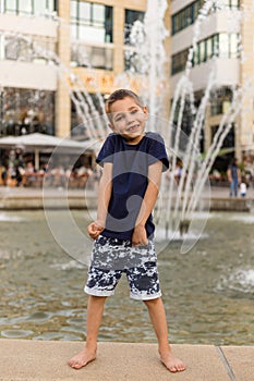 A cheerful boy stands near the fountain. Happy childhood. Parenting, Freedom
