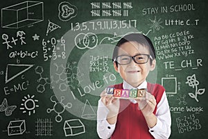 Cheerful boy student holding LEARN block