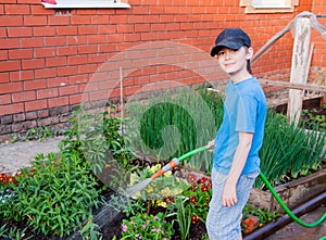 Cheerful boy watering flowers in the garden