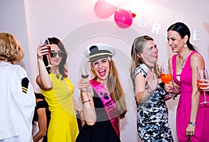 Cheerful bride and bridesmaids celebrating hen party with drinks