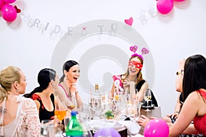 Cheerful bride and bridesmaids celebrating hen party with drinks