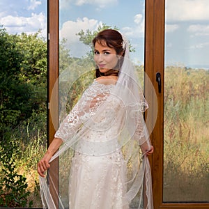 Cheerful bride in front of window