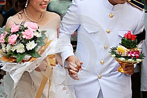 Cheerful bride and groom holding hands in Thai traditional wedding ceremony. Selective focus and shallow depth of field.
