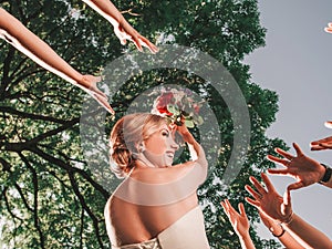 Cheerful bride throws a wedding bouquet to her friends.