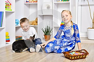 Cheerful brother and sister playing with a rabbit