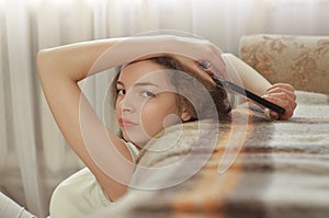 Happy brunette girl talking on mobile phone while sitting near couch