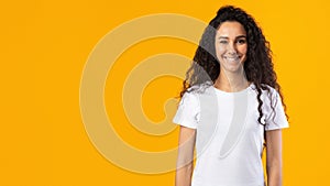 Cheerful Brunette Lady Wearing White T-Shirt Standing Over Yellow Background