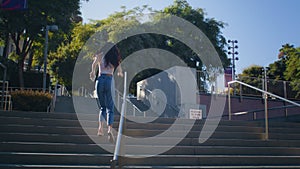 Cheerful brunette running upstairs. Asian girl ascend staircase to take picture.